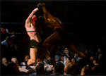 Two wrestlers, one white and one a man of color, fight in a ring surrounded by onlookers